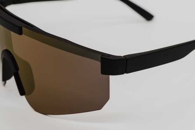 Vista en ángulo de las gafas de sol FUEGO mostrando su diseño aerodinámico y patillas flexibles.