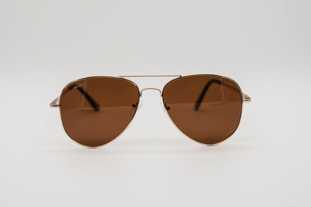 Vista en perspectiva gafas de sol New York estilo aviador doradas con lentes marrones.