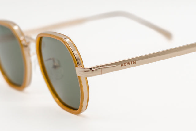 Detalle macro de la estructura metálica dorada y el aro de acetato mostaza del modelo Sidney.