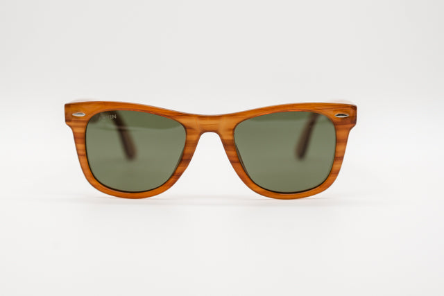 Vista en perspectiva gafas de sol Singapur con patrón veteado ámbar y lentes verdes.